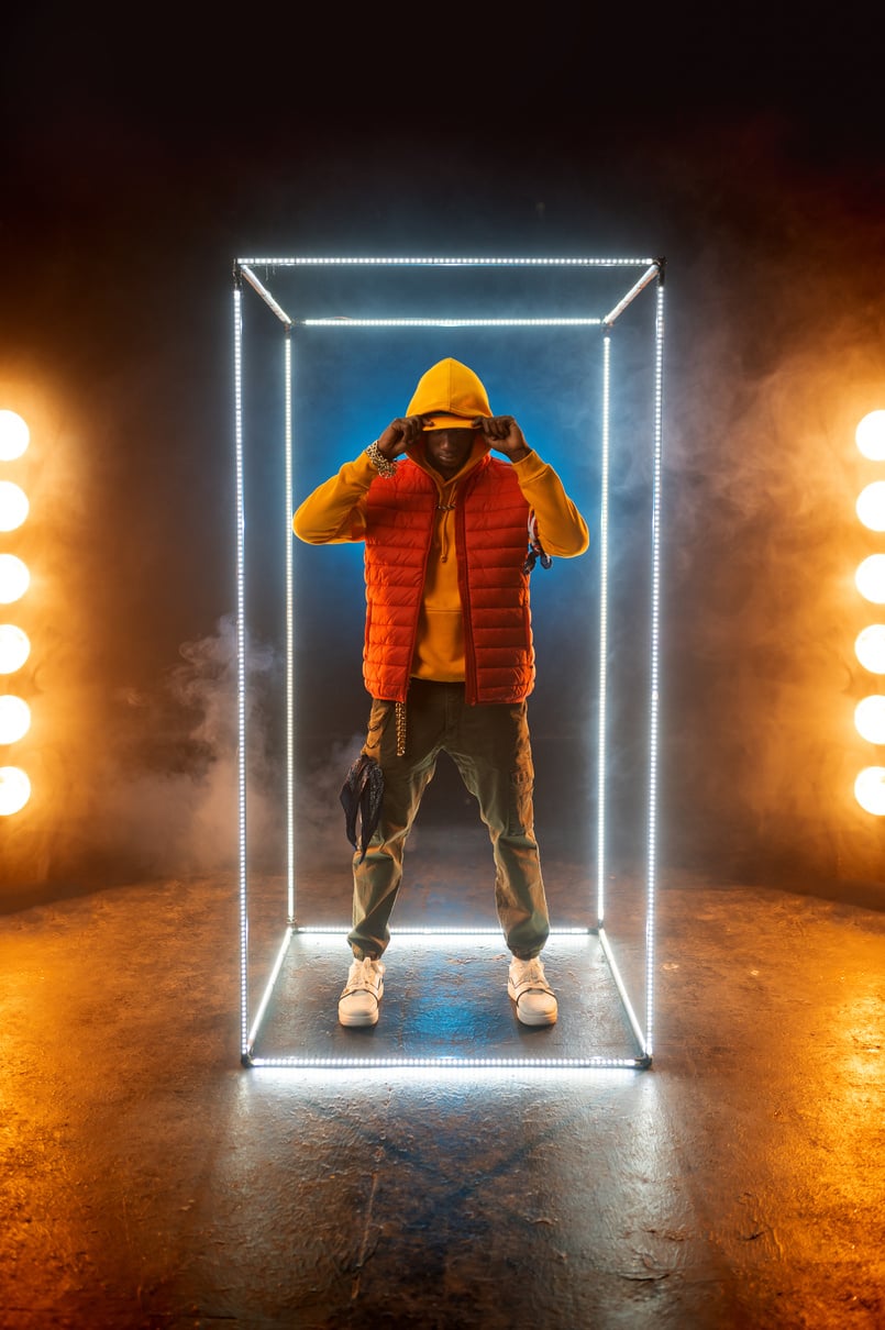 Stylish Rapper Poses in Illuminated Cube